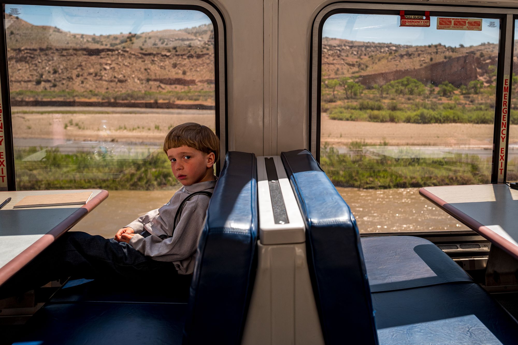 Mennonite boy sits alone in an Amtrak sightseer booth